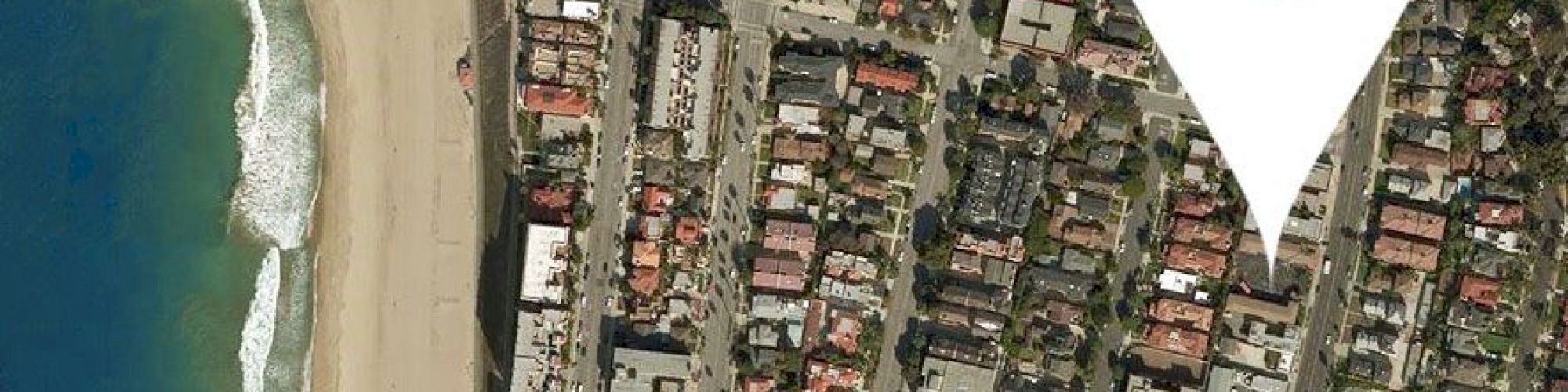 The image shows an aerial view of a coastal town with a prominent location pin marker placed on one area.