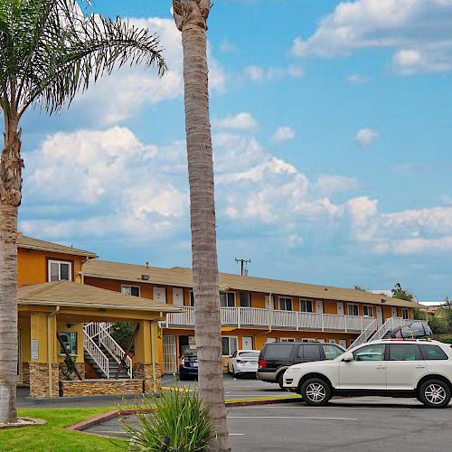 This image shows the exterior of a Redondo Inn & Suites motel, including a parking lot, palm trees, and a sign offering free Wi-Fi to guests.