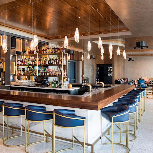 This image shows a modern bar area with a well-stocked liquor shelf, stylish bar stools, and contemporary lighting fixtures, creating a cozy atmosphere.