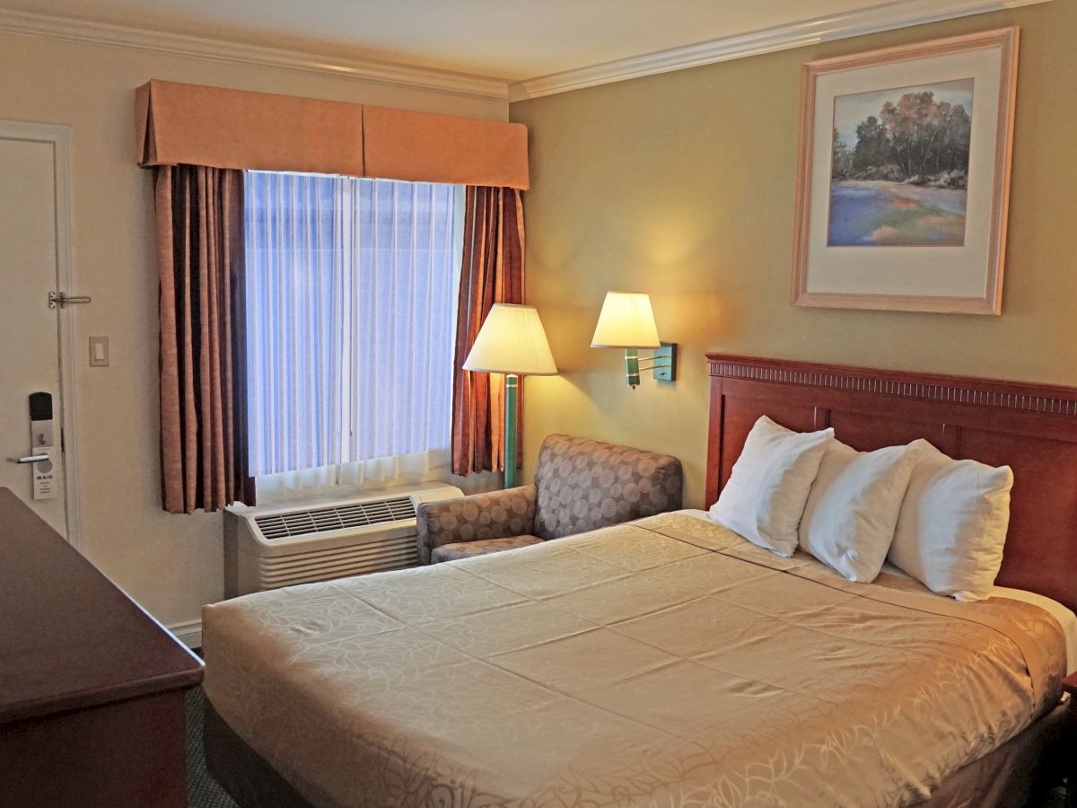 The image shows a cozy hotel room with a large bed, lamps, a window with curtains, a TV, and artwork on the wall, ending the sentence.